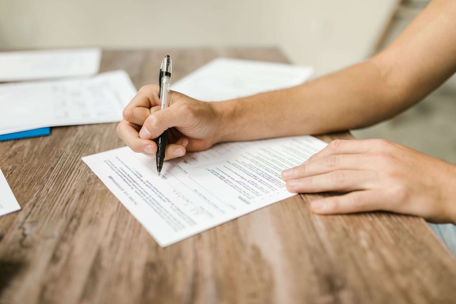 Veteran's hands completing forms for an abdominal mesothelioma VA claim at a home desk