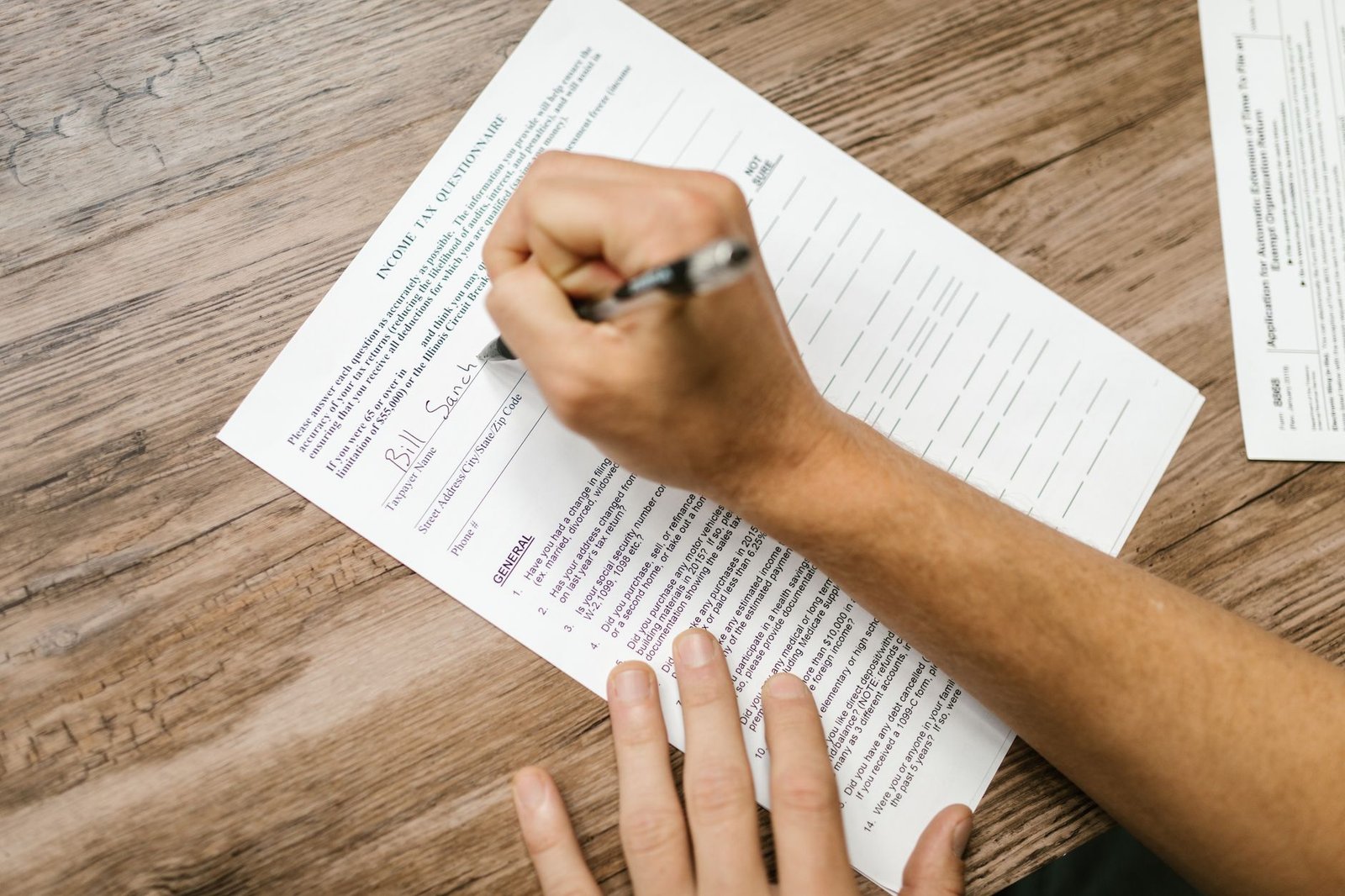 Hands completing VA disability compensation claim forms for a mesothelioma diagnosis