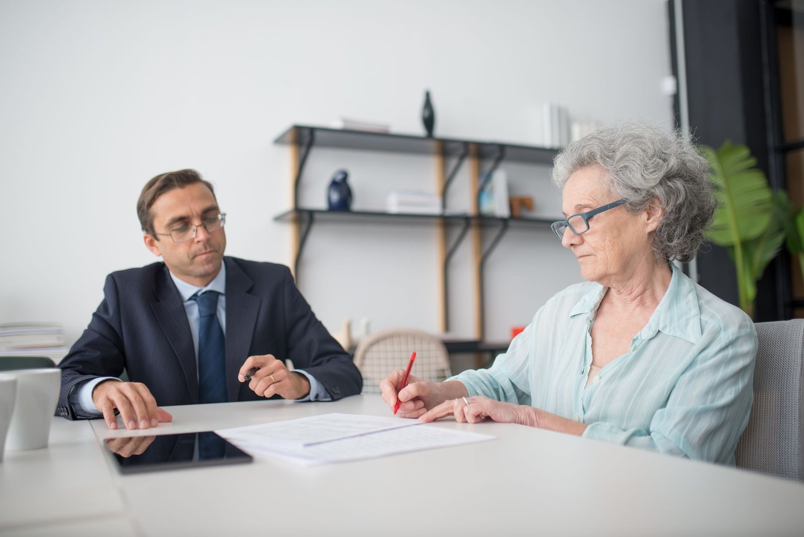 Older veteran reviewing pleural mesothelioma VA compensation paperwork with an advisor across a desk